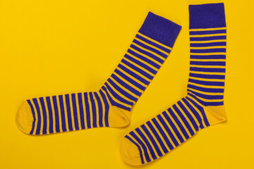 a pair of blue socks with yellow stripes, lies on a yellow background