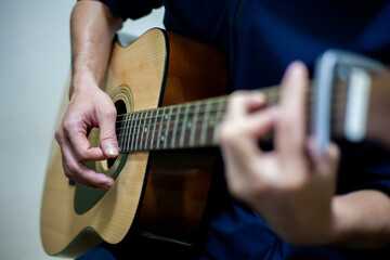 Fototapeta premium Close-up of man's hand playing acoustic guitar Musical instruments for leisure or hobbies. Practice playing the guitar.