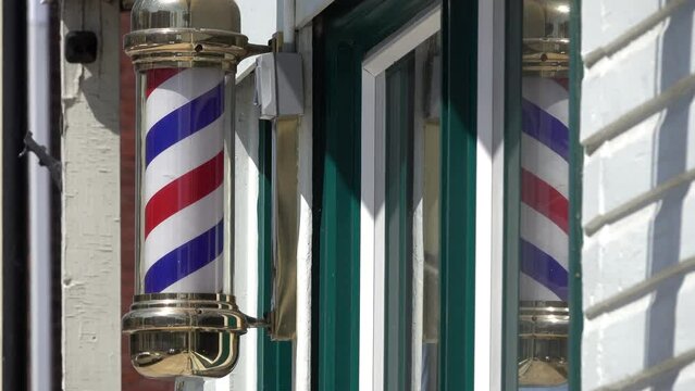 Close-up of turning barber pole with reflection in window.