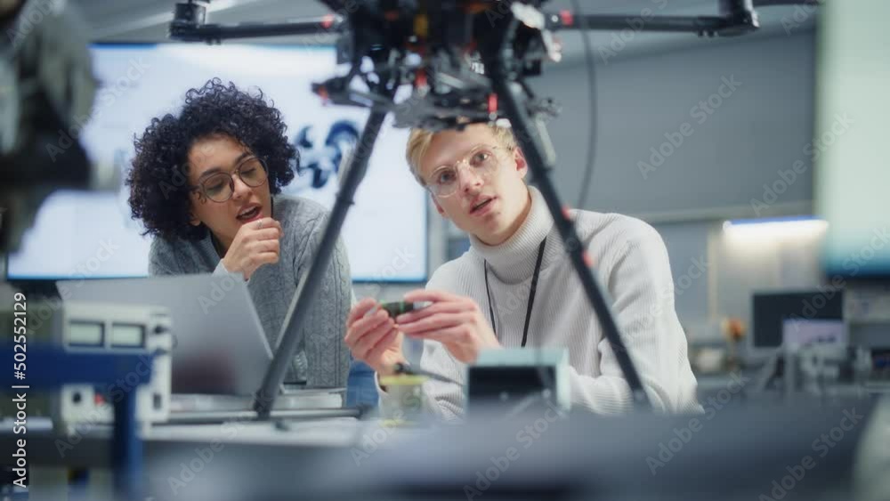 Poster Two Diverse Developers Brainstorming and Programming while Work Together on a New Drone. Colleagues Building, Configuring and Testing Drones. Progressive Technologies Concept. Slow Motion