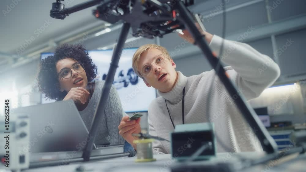 Poster professional young black developer coding at laptop while her male colleague holding semiconductor a