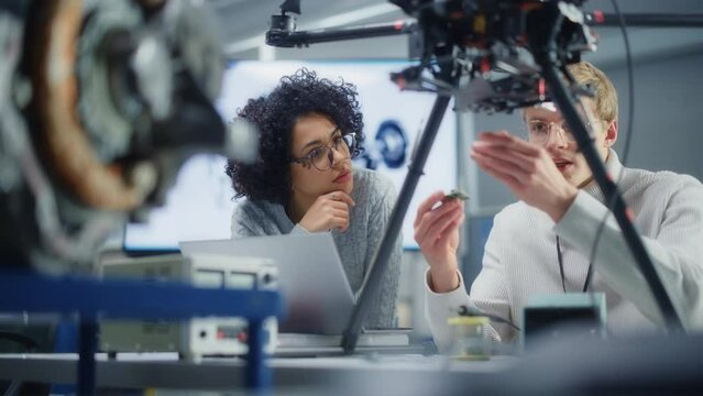 Diverse Engineers Discussing Microchip and Put it Into the Drone. Startup and Innovative Technologies in Unmanned Aerial Vehicle Concept. Portrait View
