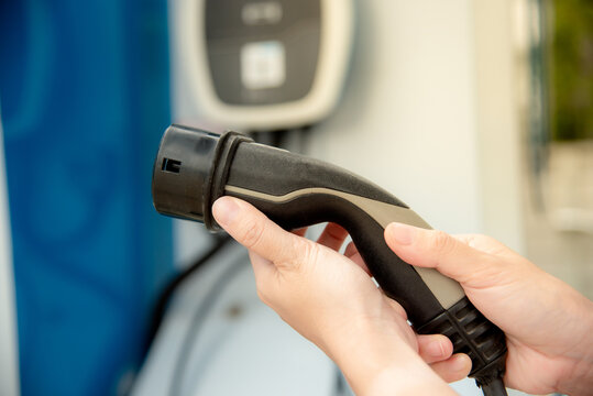 Woman Holding Electric Charger Head For Electric Car.EV Car Charger.