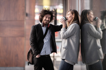 Business people on a coffee break. Man flirting with a girl outdoors. Window with reflections..