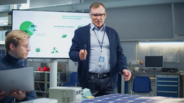 Chief Engineer Point at Projection Screen and Talks About Green Energy and Solar Panels Future Possibilities. Engineering and Sustainable Energy Education Concept. Portrait View