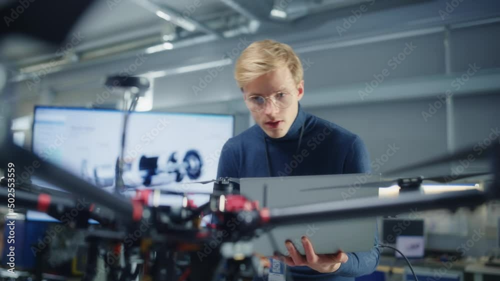 Poster caucasian male aviation engineer uses laptop computer to write programme for drone at factory. break