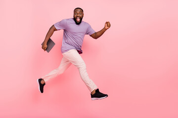 Fototapeta na wymiar Photo of excited cute guy dressed violet t-shirt running holding modern gadget empty space isolated pink color background
