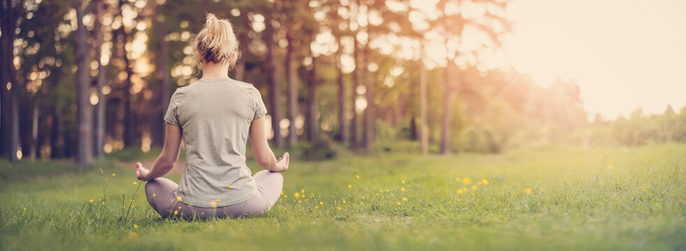Woman sitting in active wear in lotus position in nature.
