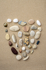Fototapeta na wymiar Sea pebbles heart shape on sand background