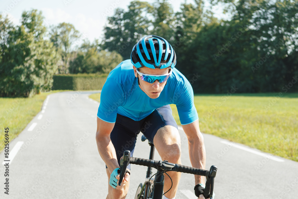 Wall mural Muscular man, professional racing bicyclist sprint cycling, with posterior raised out of the saddle and pedaling hard