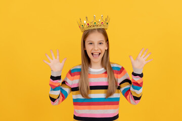 glad teen child in queen crown on yellow background