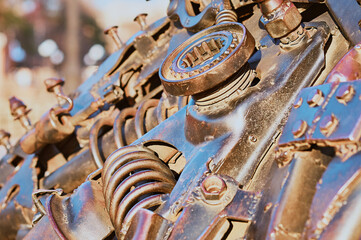 Abstract rusty mechanism. Machine parts. Levers and springs. Nuts and bolts. Metal structure outdoors in the rays of the setting sun.
