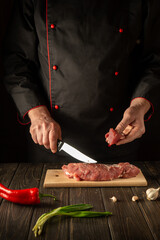 The chef cuts beef raw meat on a cutting board before barbecue. Asian cuisine. Preparing a delicious meal in the kitchen