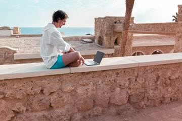 freelancer with a laptop in his hands works on vacation
