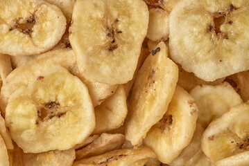 Banana chips background top view. Dried banana slices texture. Heap of dried bananas.