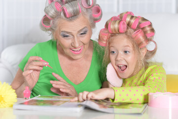 Happy grandmother with her granddaughter reading magazine