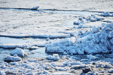 Blocks of ice floes float on the river. The beginning of the ice drift. Whirlpools and strong currents of cold water.