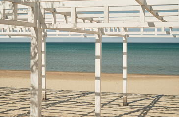 Naklejka na ściany i meble Beach wooden awnings on an empty sandy beach, selective focus. Vacation at the seaside resort.