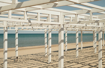 Fototapeta na wymiar Beach wooden awnings on an empty sandy beach, selective focus. Vacation at the seaside resort.