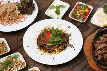 appetizers next to red meat on french fries on white plate