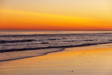 
Sunset on beach with reflections of the orange sky in the water