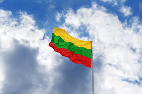 Flag of Lithuania is waving in front of blue sky and clouds