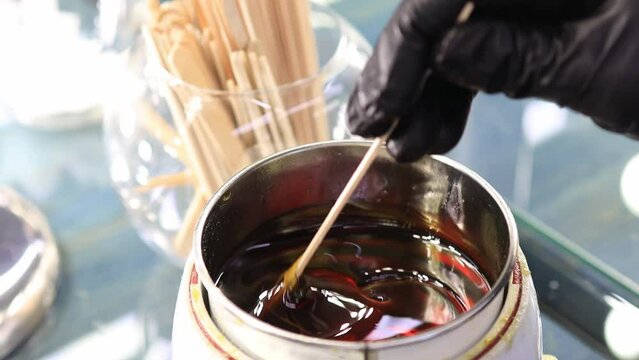 hot wax for depilation is heated by a special device. Before the depilation procedure, the master mixes the wax with a wooden spatula.