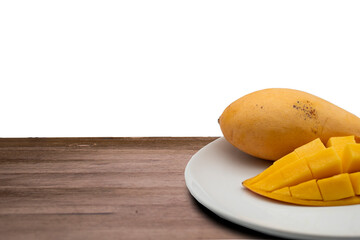  The mango slice is cut into cubes on a white plate placed on a wooden table ready to eat. In the white background. Side view. workspace.