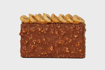 Front view image of sweet piece of chocolate cake decorated with nuts isolated at white background.