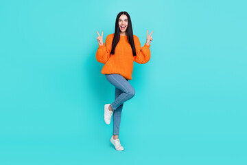 Fototapeta na wymiar Photo of confident excited woman wear orange sweater showing two v-signs smiling isolated turquoise color background