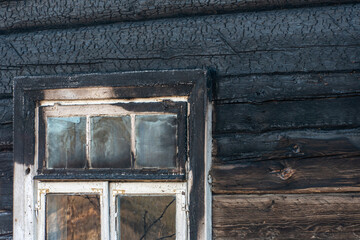 A wooden private house destroyed after a fire. The consequences of a forest fire in the village. Charred walls of a timber house close-up.