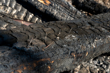 A wooden house in the village burned down because of a forest fire. Charred boards and various things lie on the ground, covered with ash and smoke.