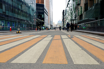 Empty crosswalk in a city, defocused view to high rising buildings and business center. People on a street with skyscrapers