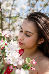 Fototapeta premium Young caucasian woman enjoying the flowering of an apple trees