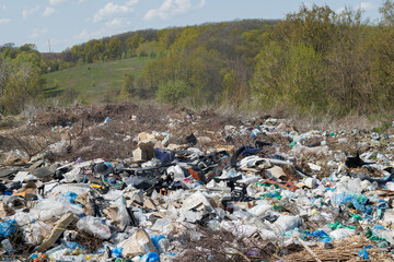 A view of the landfill. Garbage dump. A pile of plastic rubbish, food waste and other rubbish. Pollution concept. A sea of garbage starts to invade and destroy a beautiful countryside scenery