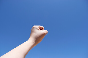 握り拳を青空に突き上げる40代女性