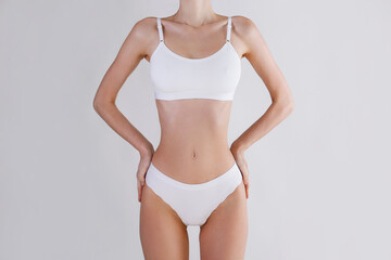 Fototapeta na wymiar Close up shot of unrecognizable fit woman in lingerie isolated on white background. Torso of slim attractive female with flat belly and thin waist in white underwear. Copy space for text.