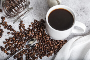 Coffee drink in a white cup and grains on the table top view. Roasted coffee beans