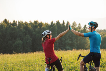 Woman and a man on racing road cycles taking a break after successful training and looking at...