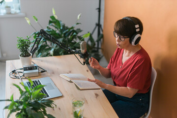 Middle-aged female radio presenter talking into the microphone and reading news - radio broadcast...