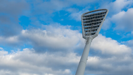 High mast on a background of a cloudy sky. Light pole under the blue sky. Space for text. Light...