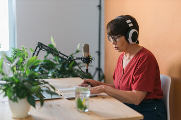 Middle-aged female radio presenter talking into the microphone and reading news - radio broadcast...