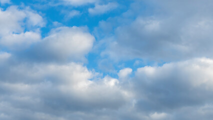 Naklejka premium Blue sky background with clouds. White cumulus clouds in blue sky. Cloudy weather, cloudscape, copy space. Space for text.