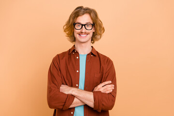 Portrait of attractive content cheeful intellectual red-haired guy folded arms isolated over beige...