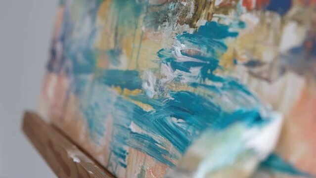 Close-up motion of a brush of an artist who paints a picture with blue paints