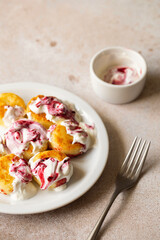 Cottage cheese pancakes, syrniki, ricotta fritters on white ceramic plate with sour cream and jam. Healthy and delicious morning breakfast. Beige background. Food for kids