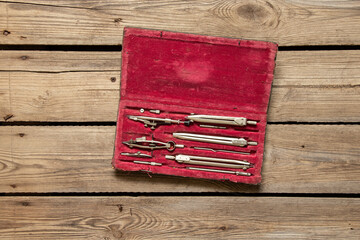 Old drawing compasses in a red box on a table, school and education, designer