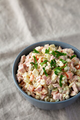 Homemade Olivier salad in a Bowl on a white wooden background, side view. Copy space.