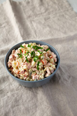 Homemade Olivier salad in a Bowl on a white wooden background, low angle view.