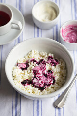Homemade cottage cheese in a deep plate. Milk product. Granular cottage cheese with black currant jam